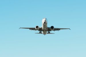 A front view of an airplane in flight against a clear blue sky, showcasing aviation.