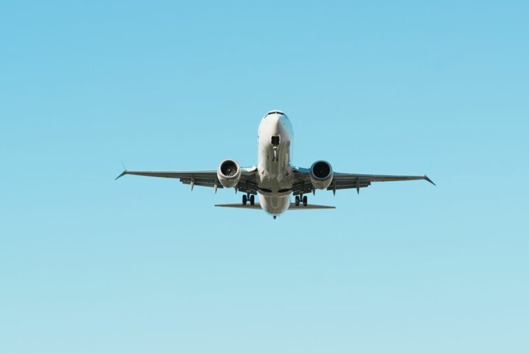 A front view of an airplane in flight against a clear blue sky, showcasing aviation.