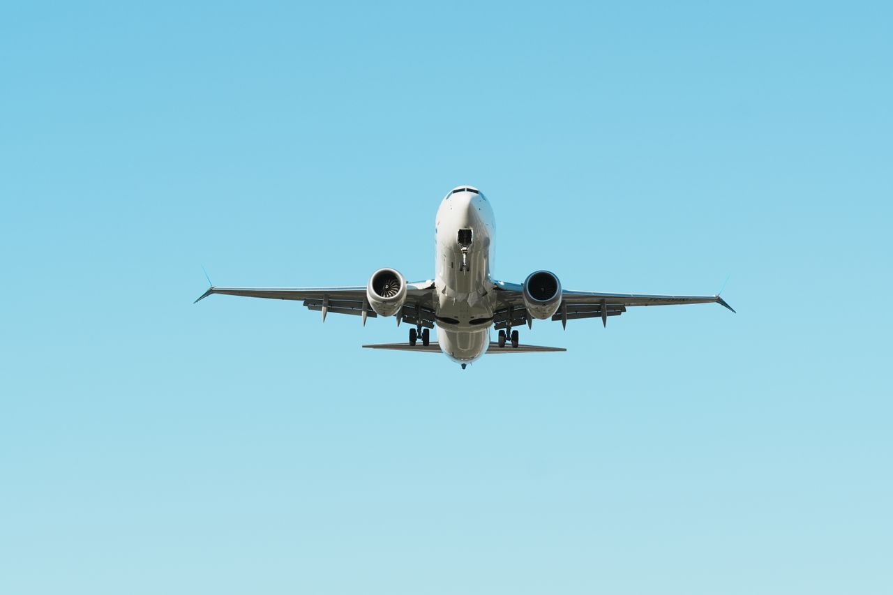A front view of an airplane in flight against a clear blue sky, showcasing aviation.